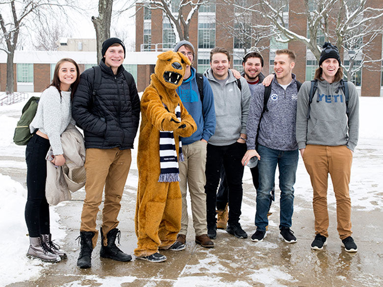 Lion standing with students in the snow. 