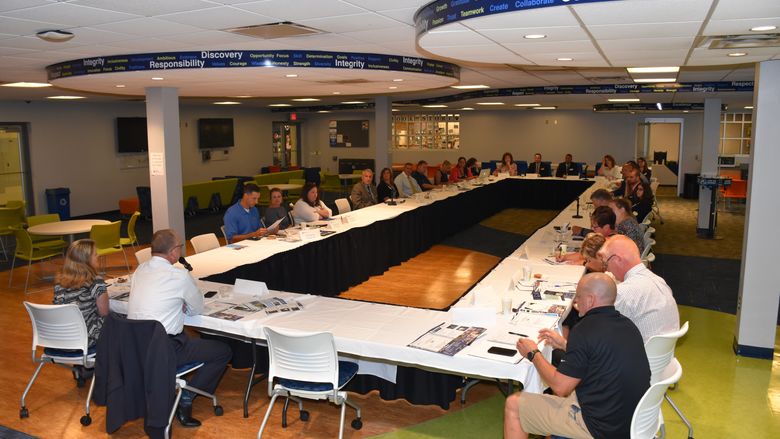 A forum of high school administrators and Penn State Fayette staff are seated around a large table in the Student Center.