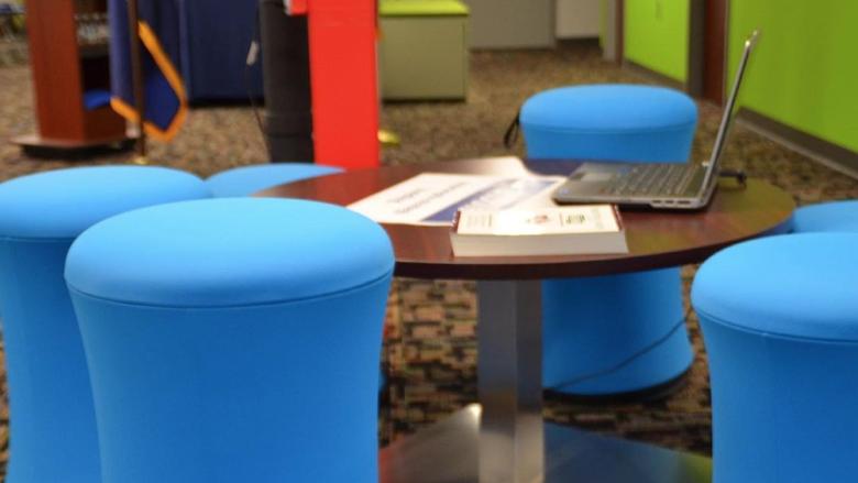 Blue stools surround a collaborative table at Fayette LaunchBox space