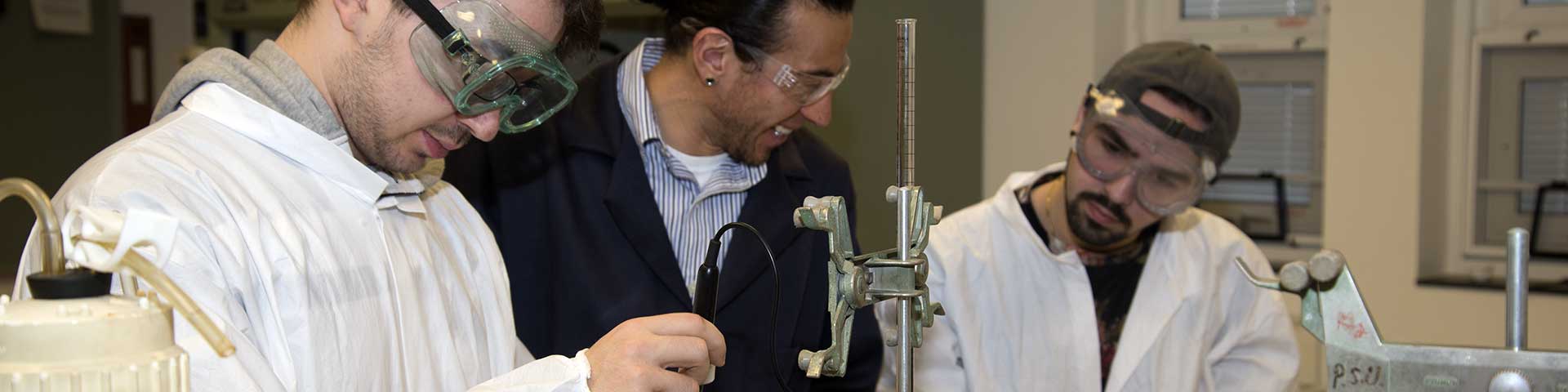 Two students working on a chemistry experiment with the professor. 