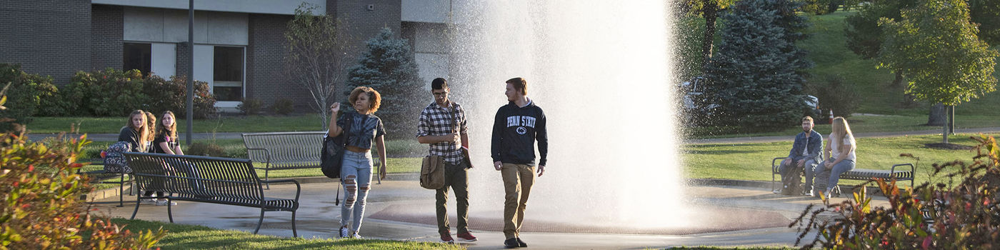 Multiple students walking around the fountain.