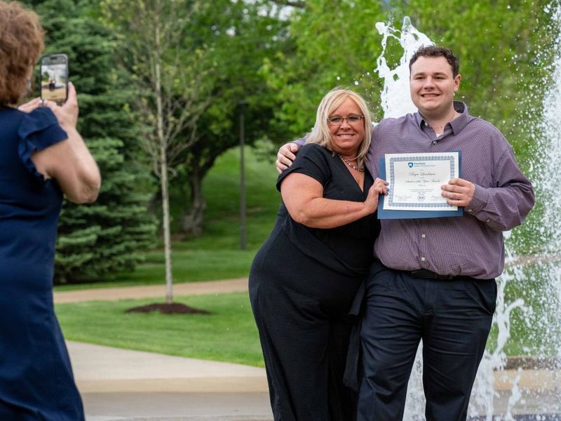 Bryce Landman poses with family by the fountain after receiving the Student of the Year award in Business at Penn State Fayette.