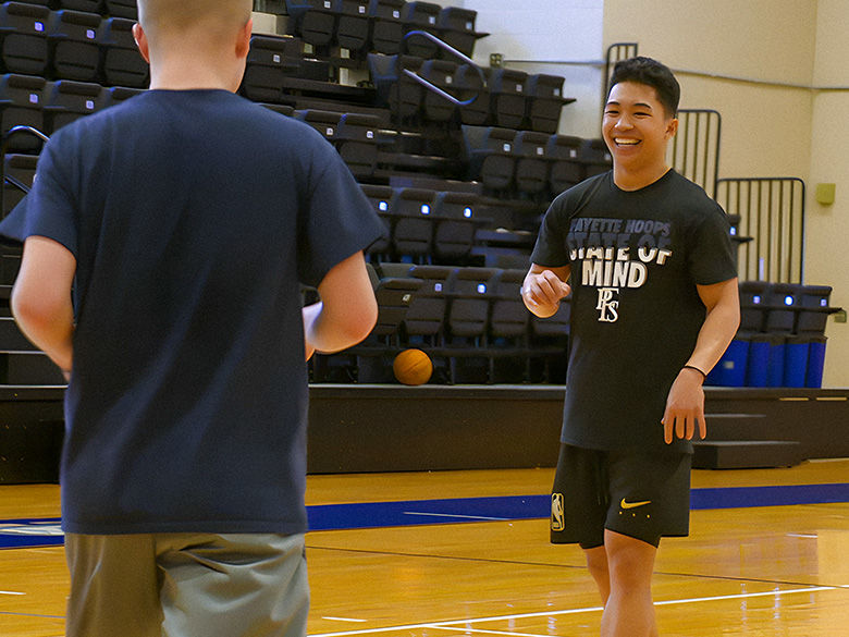 Two male students practicing basketball in the main arena.