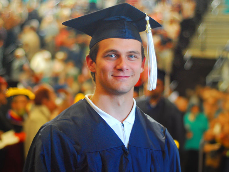 A graduate smiling at the camera.