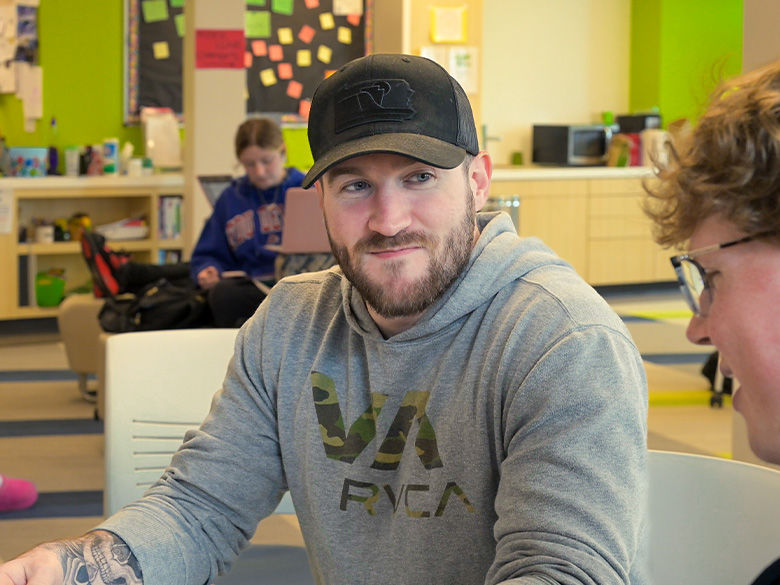 A student in the success center, smiling towards his friend.