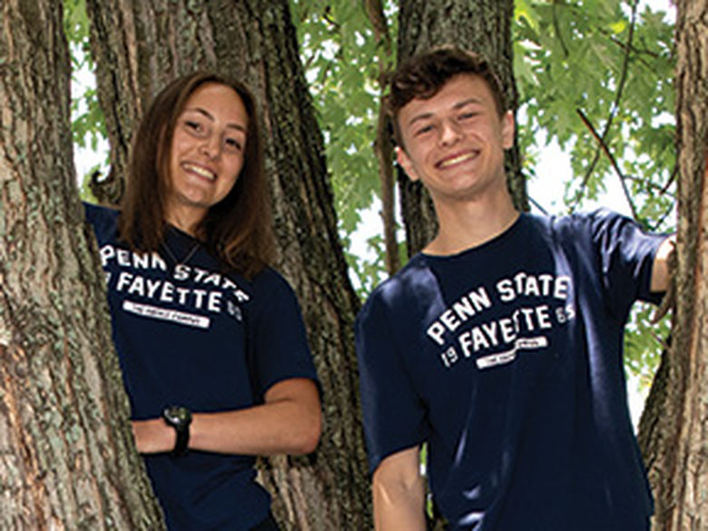 Two students smiling in a tree.