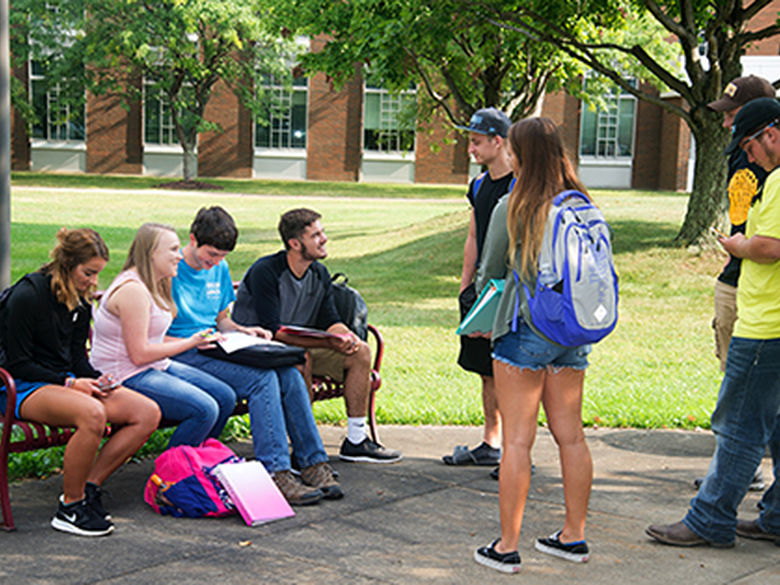 Students outside on a bench talking.