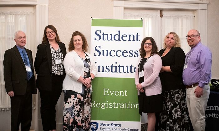 A group of people pose before a sign that reads "Student Success Institute."