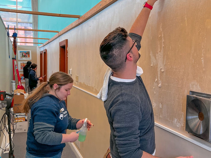 Two Penn State students repainting a wall