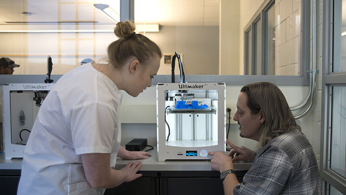Nate showing a student the 3D printer.