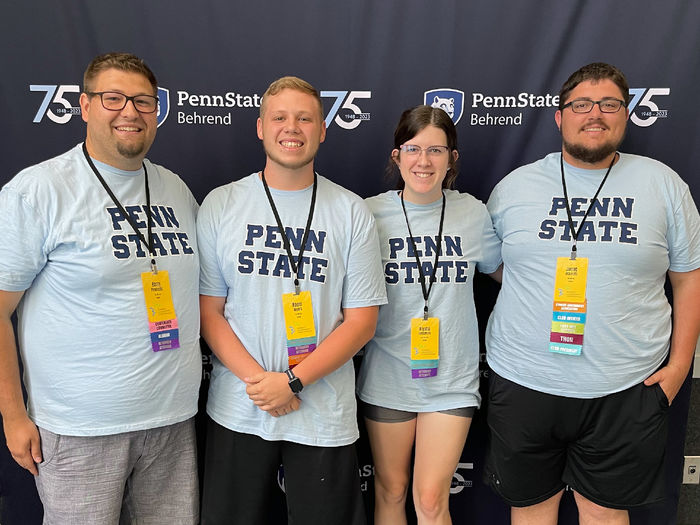 Students posing in front of a Penn State backdrop.