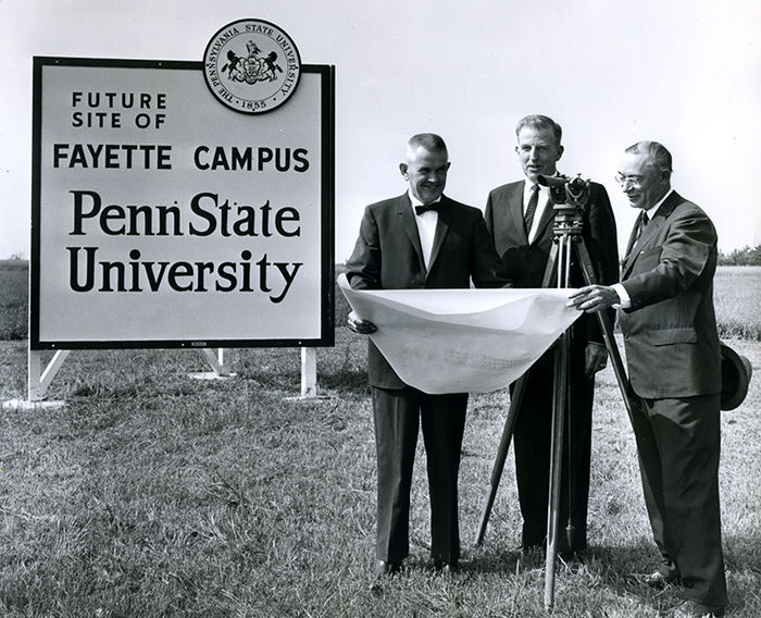 Future site of campus sign with three people.
