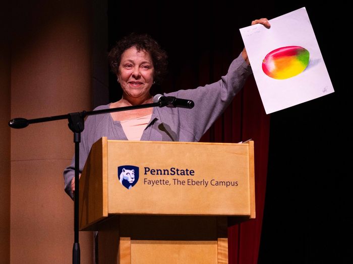 A presenter holds up Emily Kimmel’s award-winning drawing on stage during the Student Awards Banquet, where Kimmel received the Jerome Joseph Guzy Memorial Award in Art.