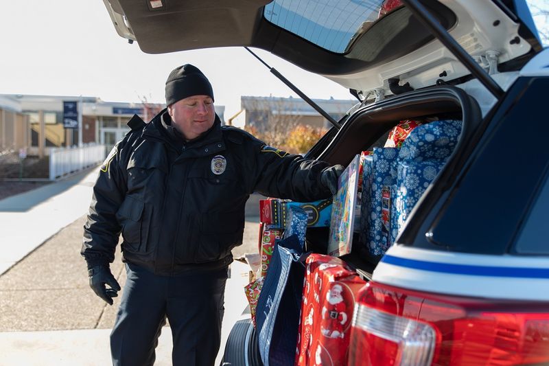 Police officer puts gift in car Police officer puts gift in car