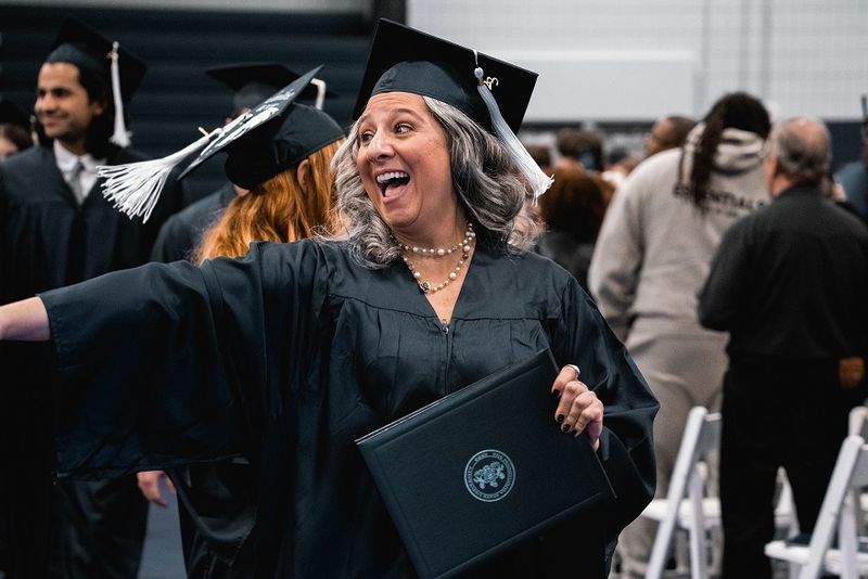 Graduate points and smiles holding diploma