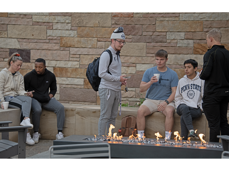 Students gather around fireplace at Outdoor Student Lounge