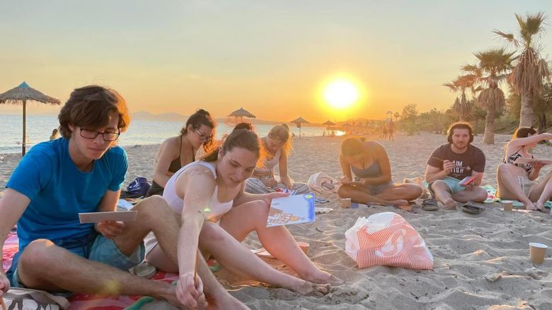The students spontaneously organized a collaborative painting activity on the beach at sunset.