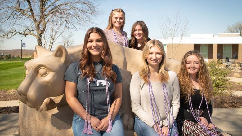 Students sitting next to the Penn State Fayette Nittany Lion shrine