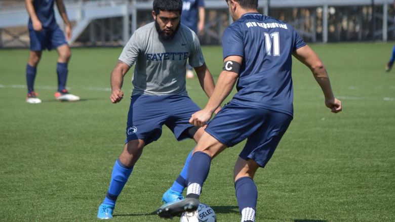 Two men playing soccer on campus.