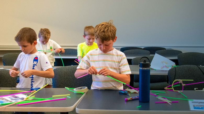 Four children practice arts and crafts inside a classroom.