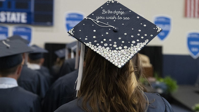 A graduation cap reads Be The Change You Wish to See