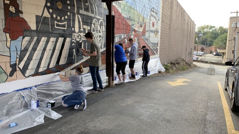Penn State Fayette students work to restore the mural “Trains of Progress.”