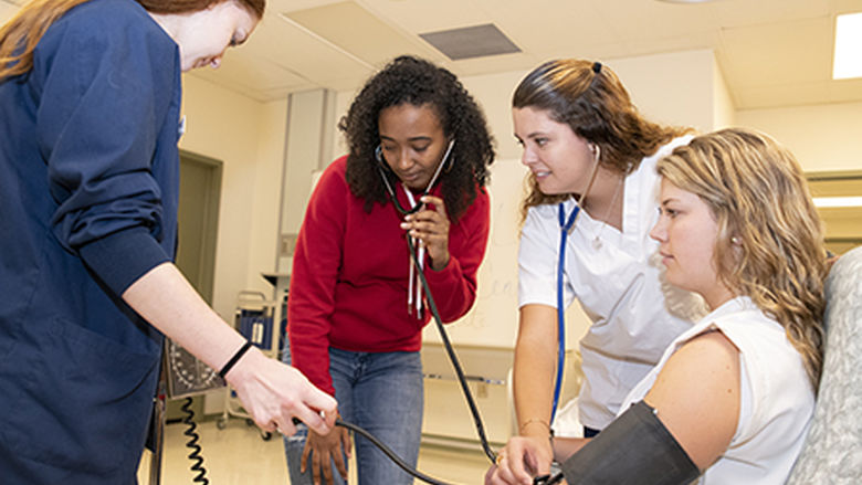 Nursing students working with blood pressure cuff.