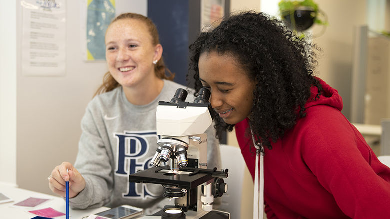 Two students working with a microscope.