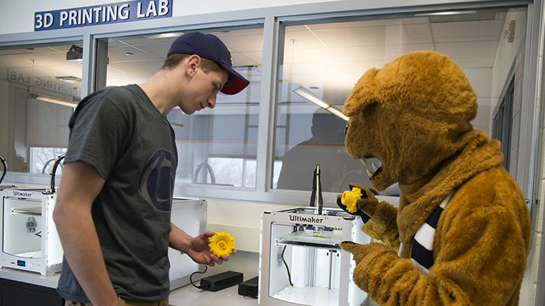 Student working in the 3D lab with the mascot.