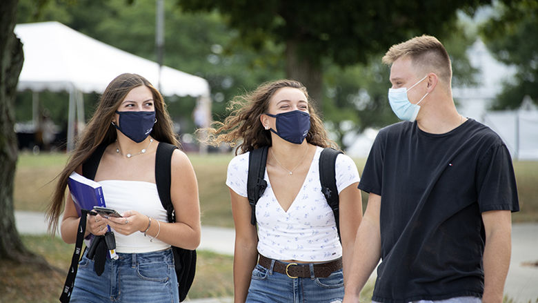 Three masked students walking on campus.