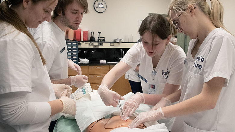 Nursing students applying their knowledge while using a simulated model.