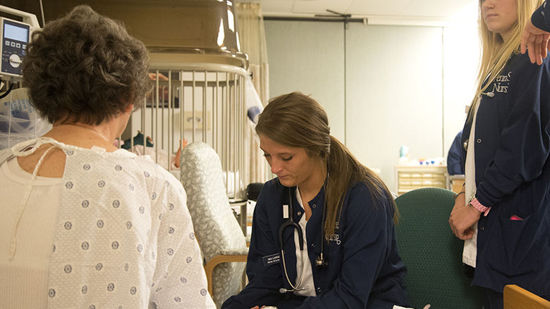 Nursing students working with a patient.