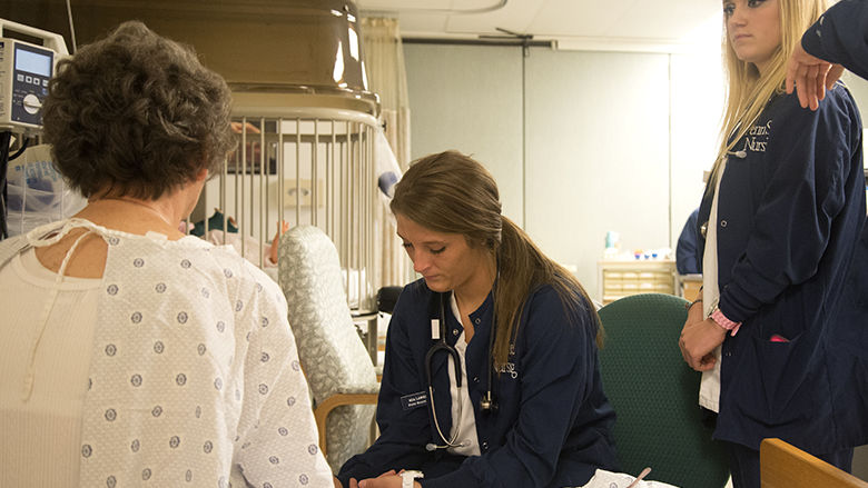 Nursing students working with a patient.