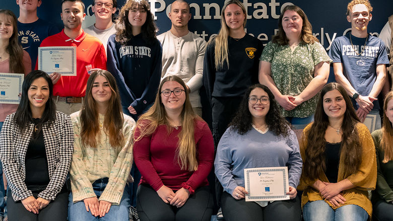 A group of Penn State Fayette students and faculty pose for a photo after an awards ceremony. Several students hold certificates for Pi Sigma Phi honor society.