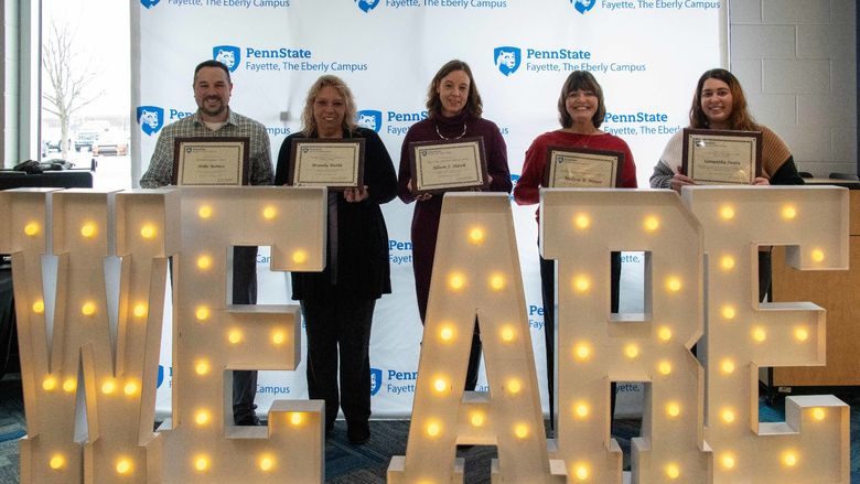 Five people standing behind the letters We Are in lights