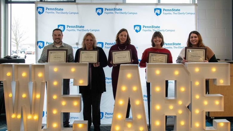 Five people standing behind the letters We Are in lights