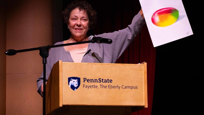 A presenter holds up Emily Kimmel’s award-winning drawing on stage during the Student Awards Banquet, where Kimmel received the Jerome Joseph Guzy Memorial Award in Art.