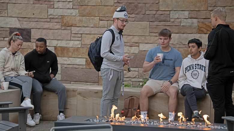 Students gather around fireplace at Outdoor Student Lounge