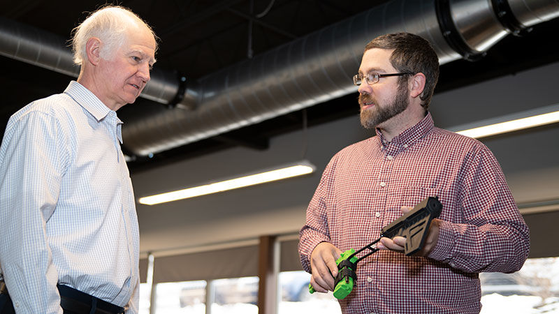 Mark Scaccia looks on as Seth Caton demonstrates use of his original brace for small sidearms.