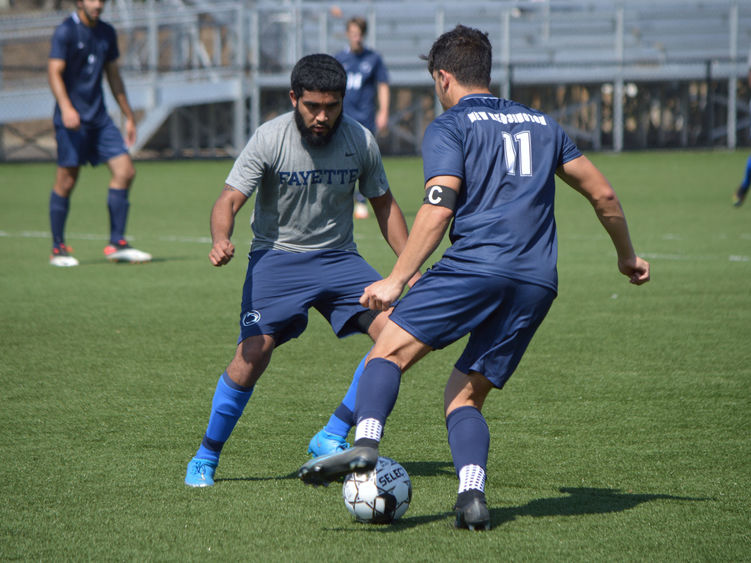 Two men playing soccer on campus.