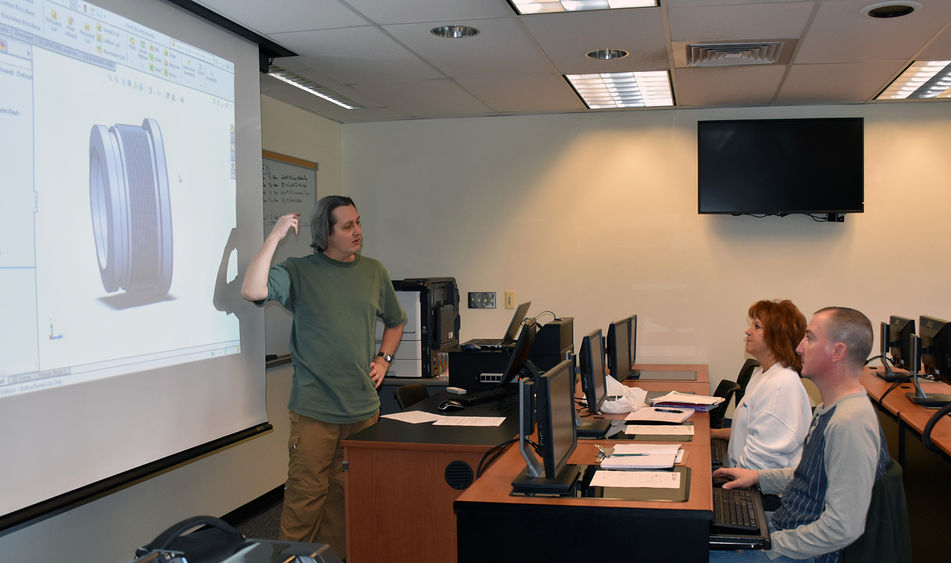 Fayette Engineering faculty member Nate Bohna instructs Darlene Means and Jerry Manchas, employees of Uniontown’s Machine Fabricating and Weight Equipment Shop, in the use of Solidworks software, which they will use to create images of manufactured parts.