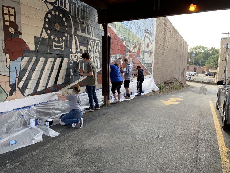 Penn State Fayette students work to restore the mural “Trains of Progress.”