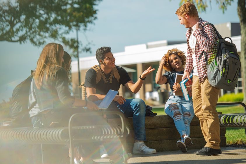 Students gather outside and talk to each other.