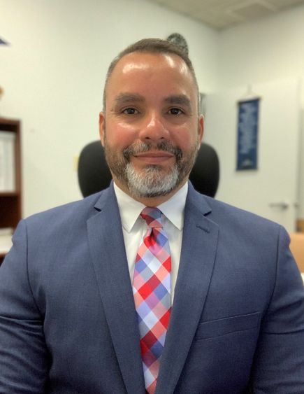 Man smiles in suit and tie for headshot.