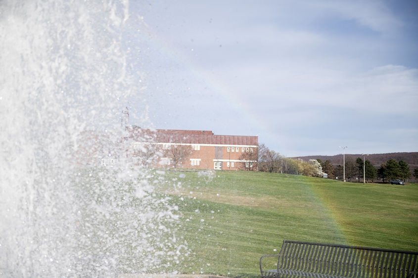 The Penn State Fayette fountain appears behind a rainbow