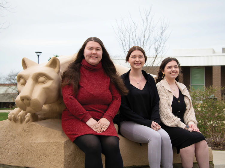 Three Nittany Lions Read and Count student workers sitting next to the Nittany Lion shrine