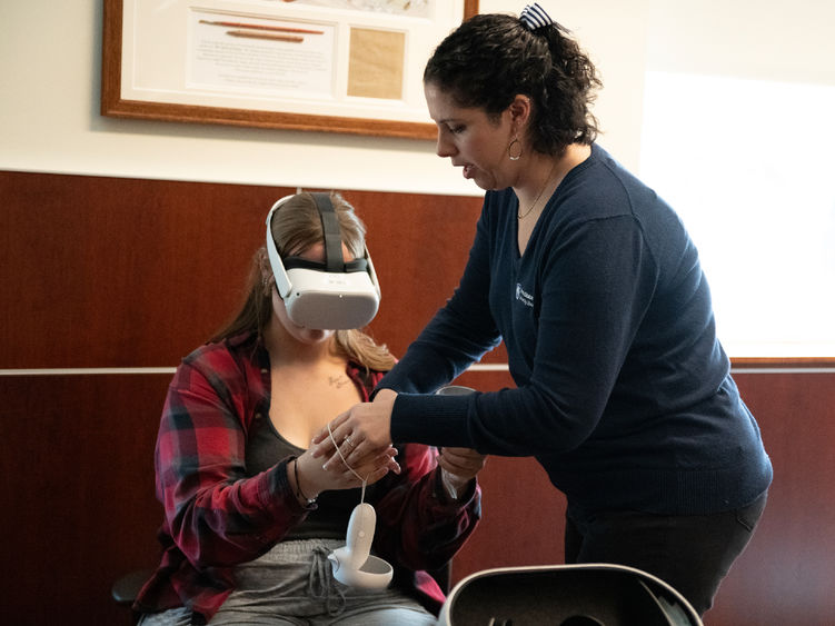 Head librarian Emma Beaver assists a student with virtual reality headgear at Penn State Fayette.