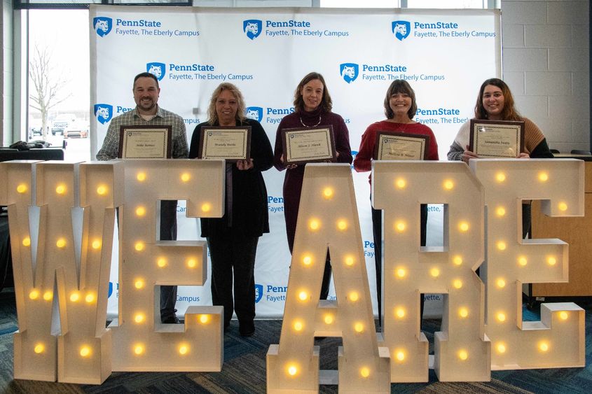 Five people standing behind the letters We Are in lights
