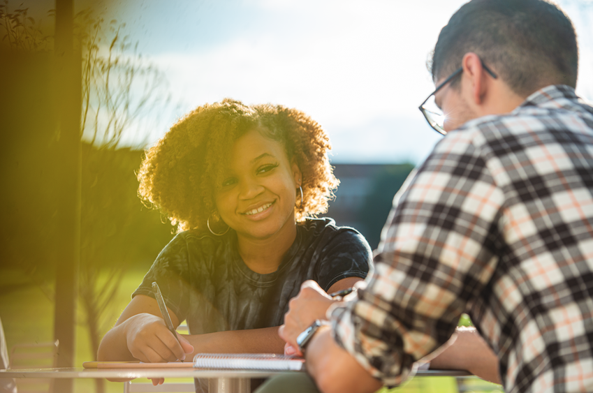 Two students share a. table outside on campus