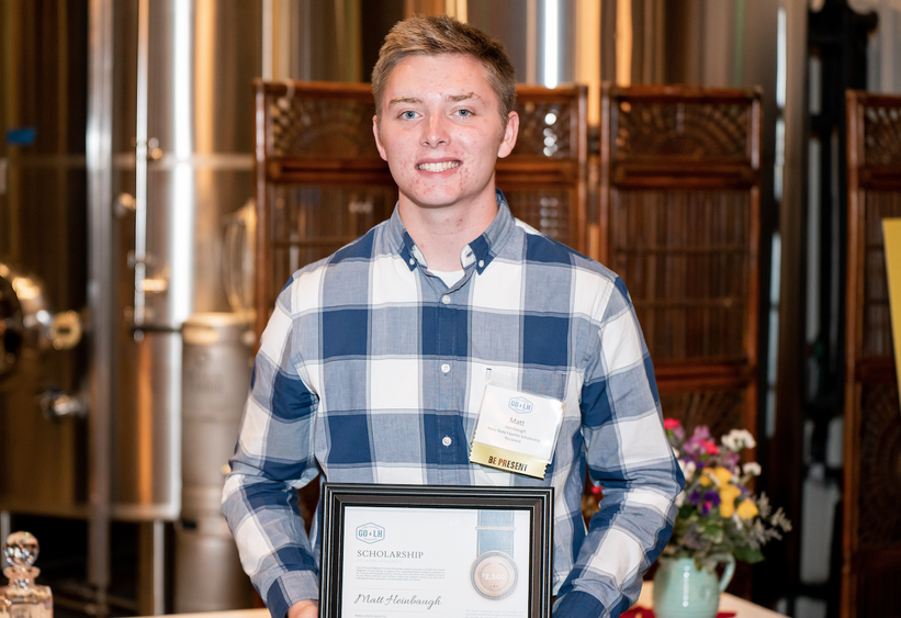 Matthew Heinbaugh holds up a certificate commemorating his scholarship award